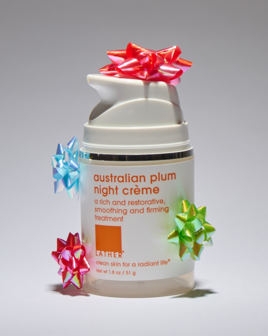 A pump jar of Lather australian plum night crème decorated with metallic gift bows in red, blue, and green.
