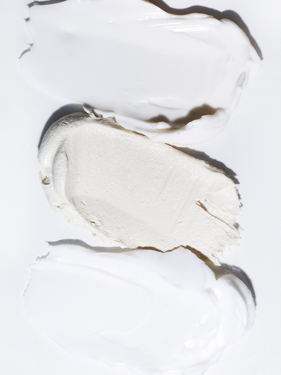 Three swatches of Lather cream textures — glossy white, matte off-white, and glossy white — smeared side by side.