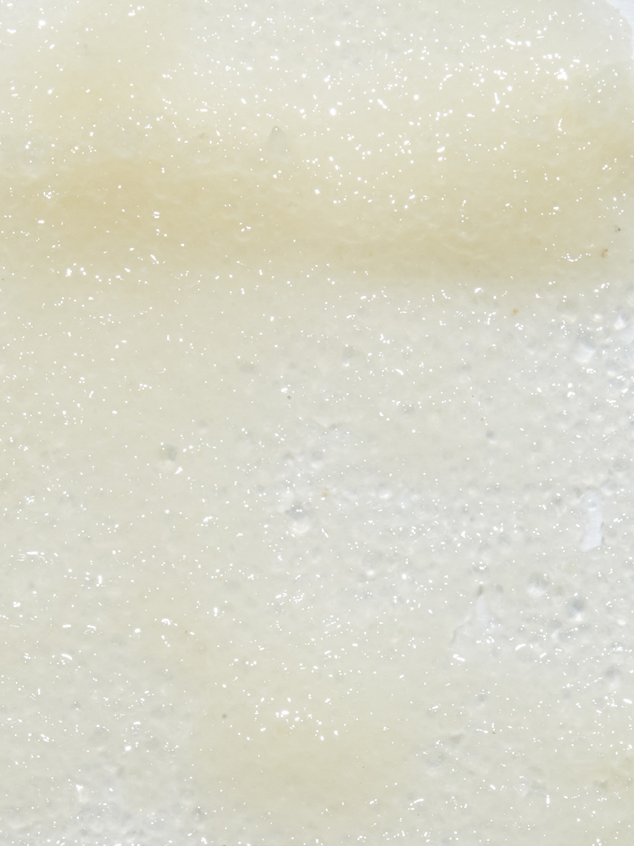 Macro close-up of a pale, glittery gel-cream texture with fine flecks throughout.