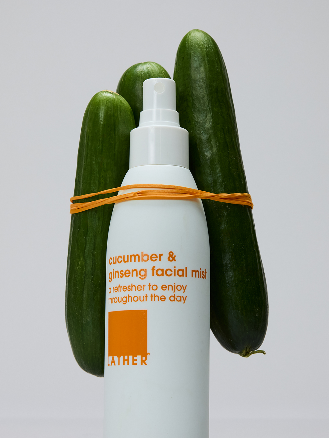 Lather Cucumber & Ginseng Facial Mist nestled between three whole cucumbers, tied together with orange raffia.
