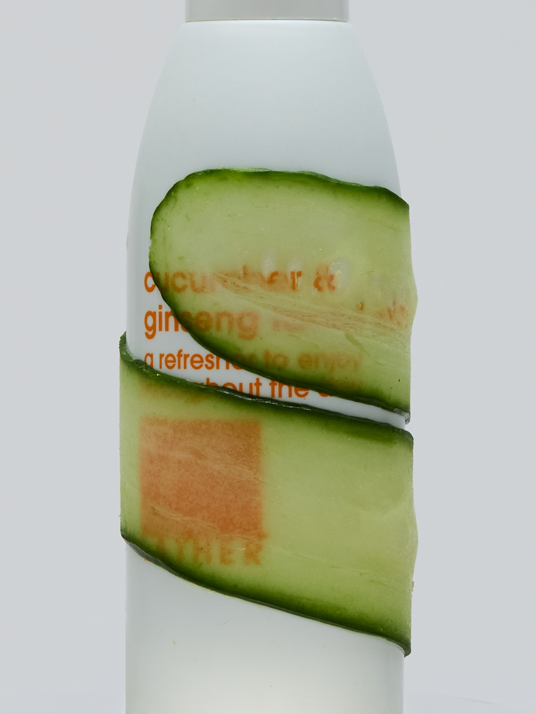Close-up of the Lather Cucumber & Ginseng bottle wrapped in a spiral of cucumber peel.