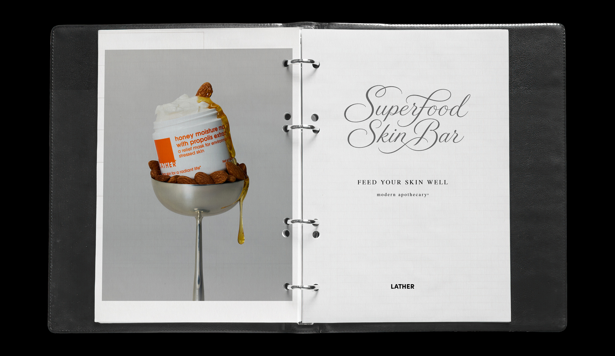 A leather binder styled as a tasting menu: a plastic-sleeved photo of the Honey Moisture Mask with Propolis Extract on the left page, and a title page reading 'Superfood Skin Bar, Feed Your Skin Well, modern apothecary' on the right.