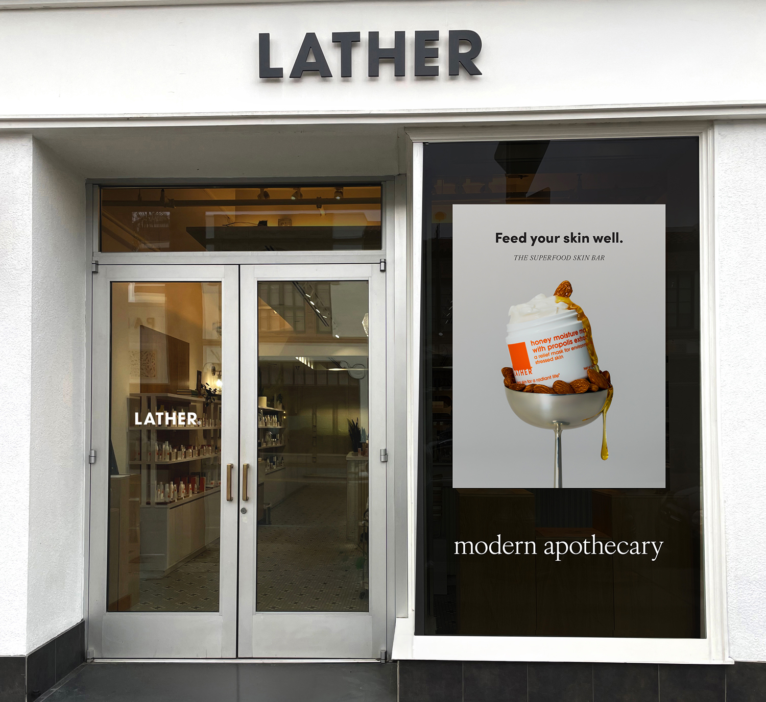 LATHER storefront with a store window decal reading 'Feed your skin well. The Superfood Skin Bar. Modern apothecary,' featuring the Honey Moisture Mask in a coupe of almonds.